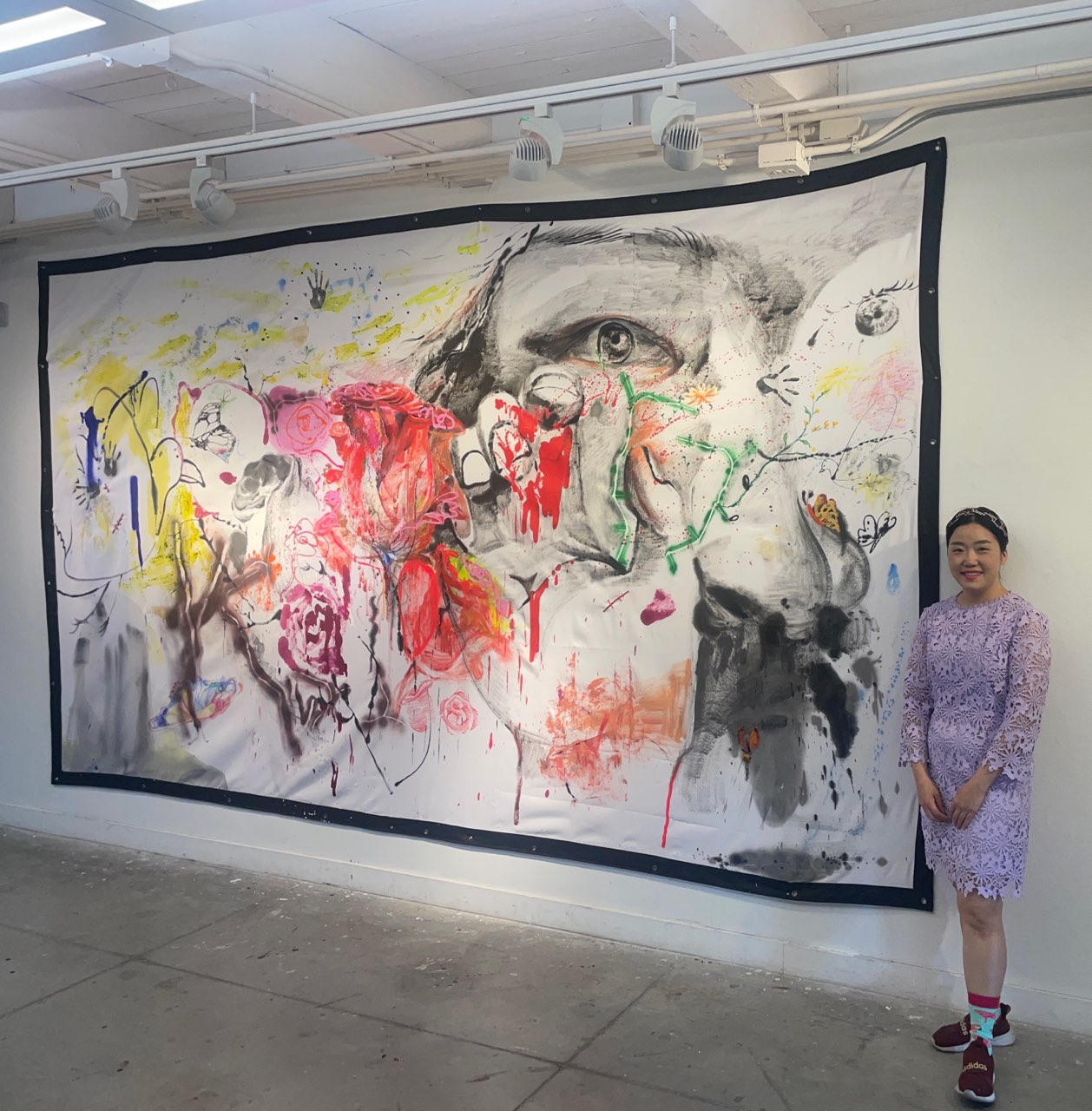 Ara Ko standing beside her large-scale painting